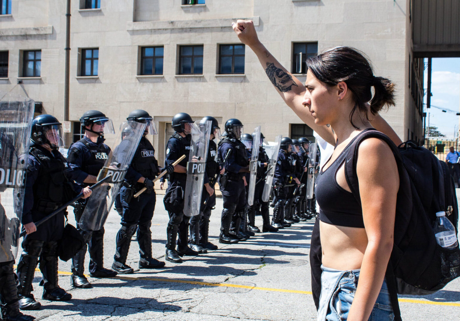 Protester raising fist facing police line