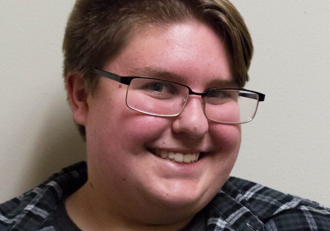 Smiling individual wearing a plaid shirt