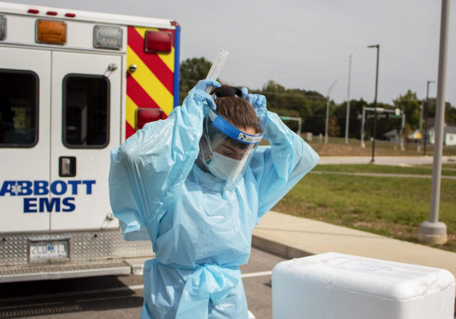 Medical professional adjusts face shield near ambulance