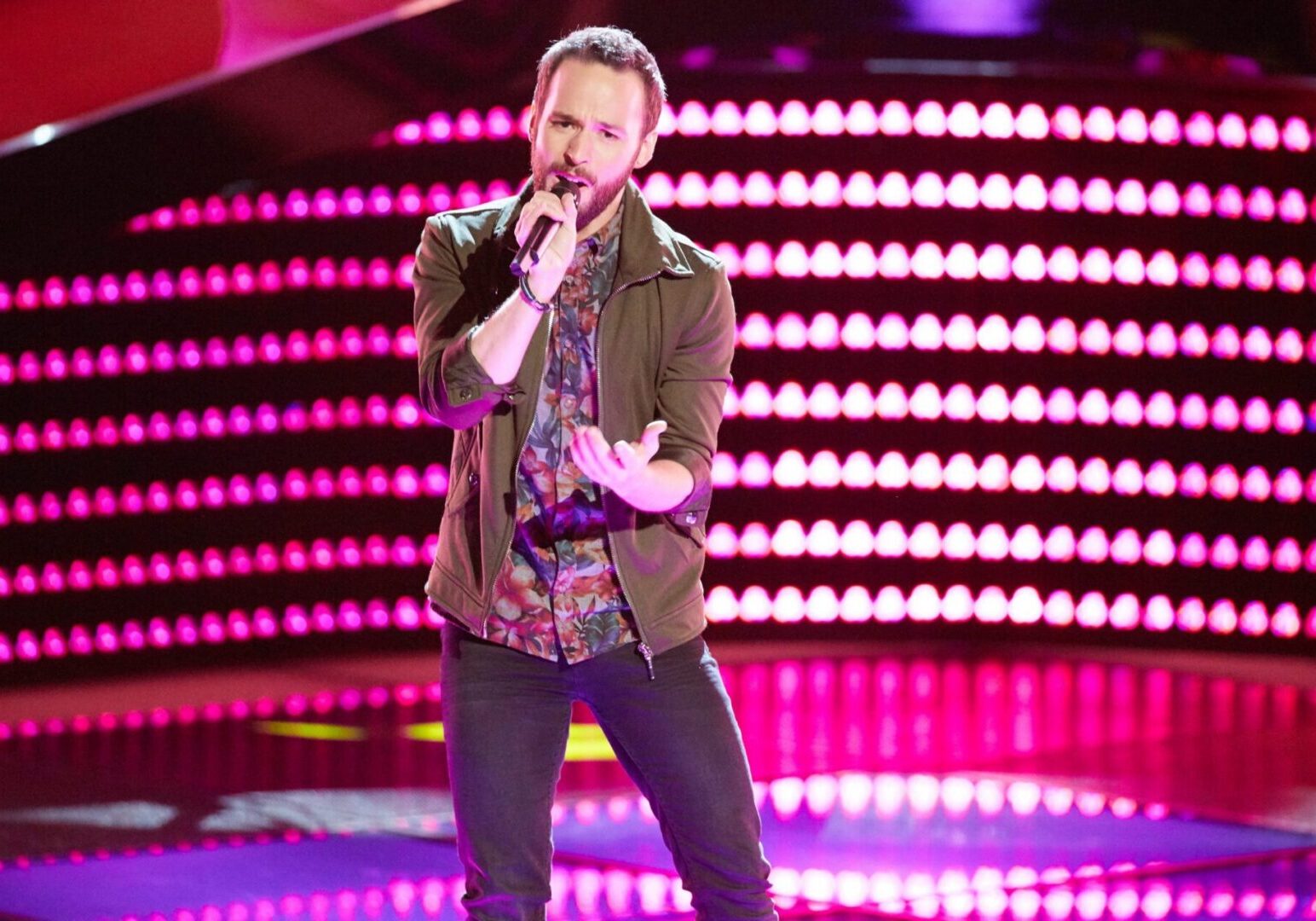 Performer holding microphone under pink lights