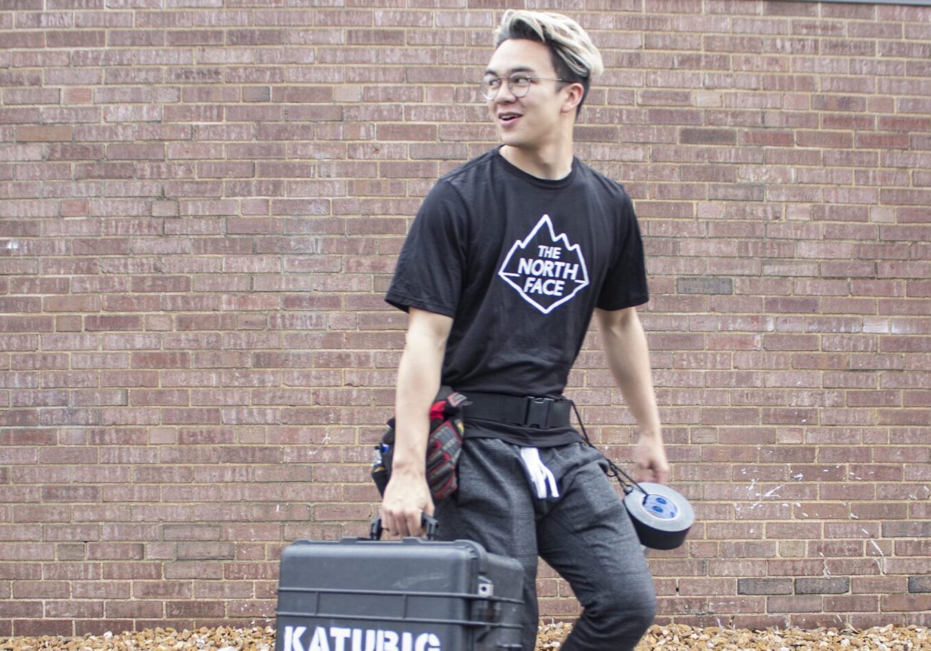 Person carrying tools against brick wall