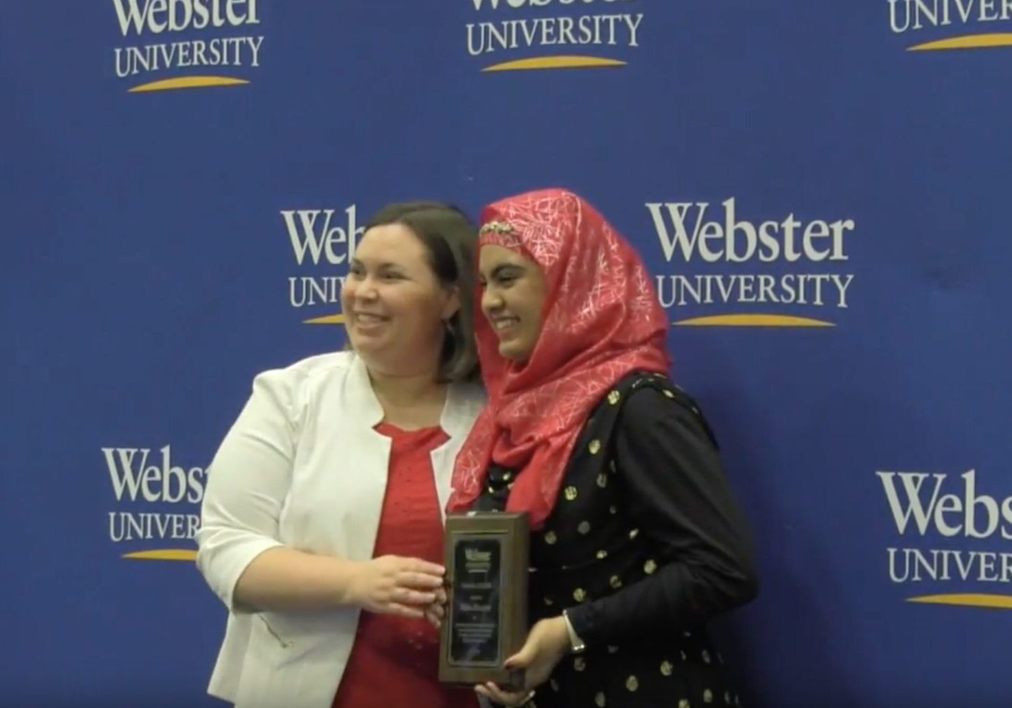 Two people posing with an award