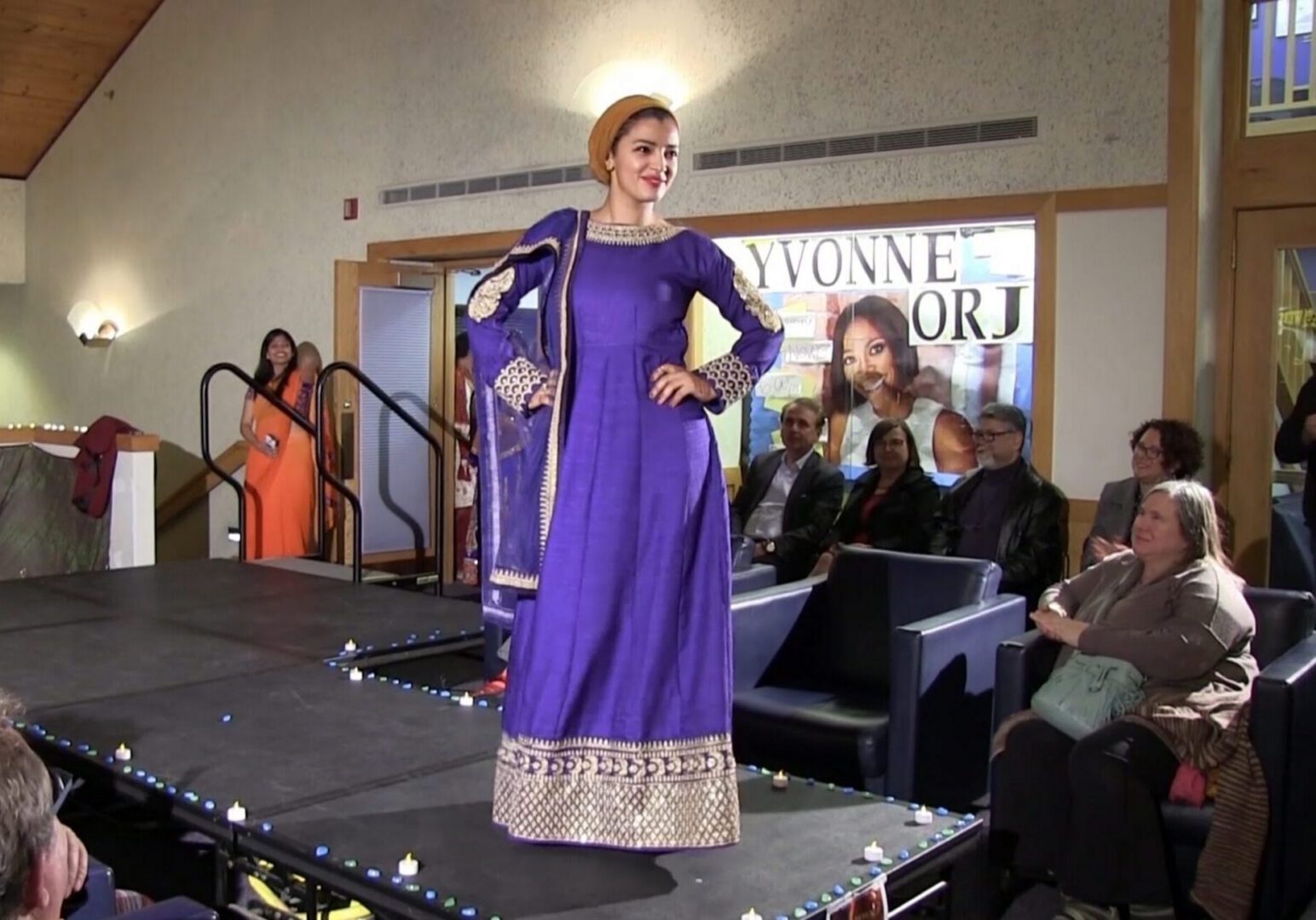 Woman modeling elegant purple attire on stage.