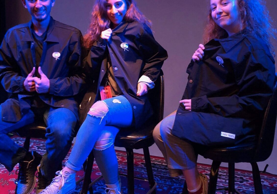 Friends posing in casual outfits on stage.