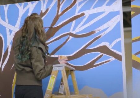 Muralist working on large tree design