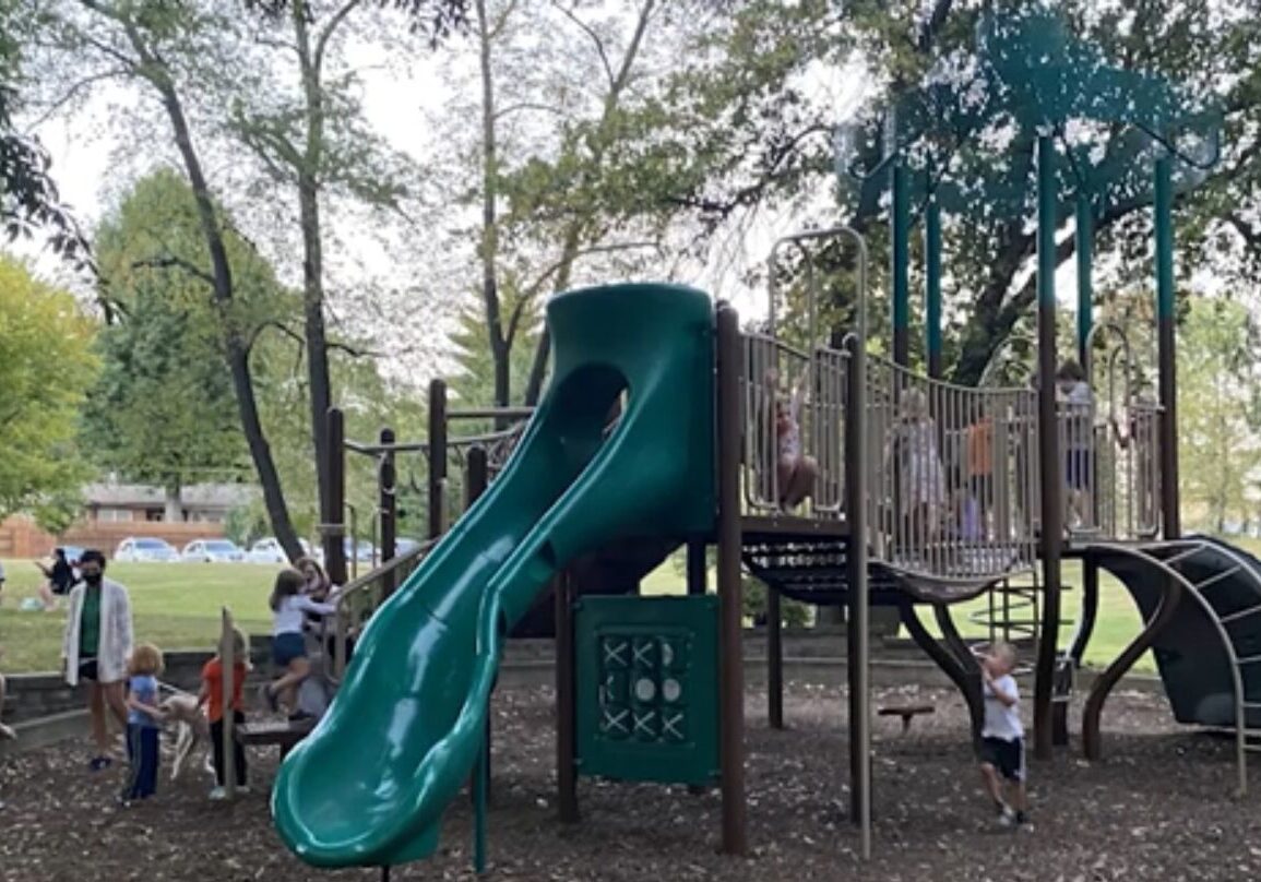Children playing on a green playground structure.