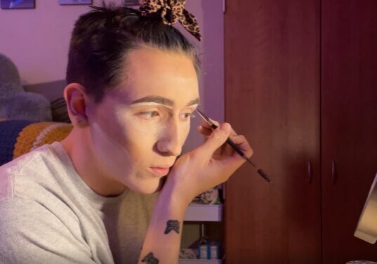 Individual using makeup brush near mirror