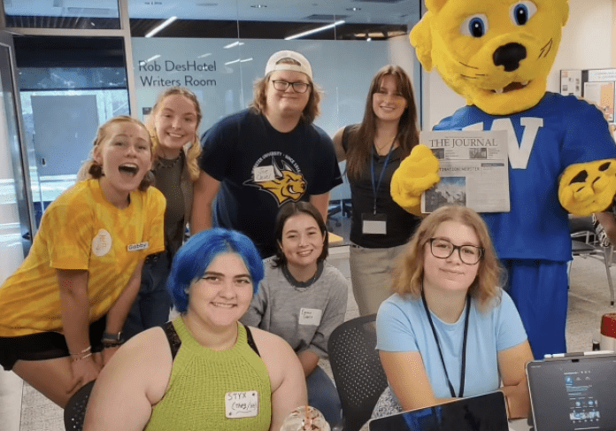 Students with mascot holding a newspaper