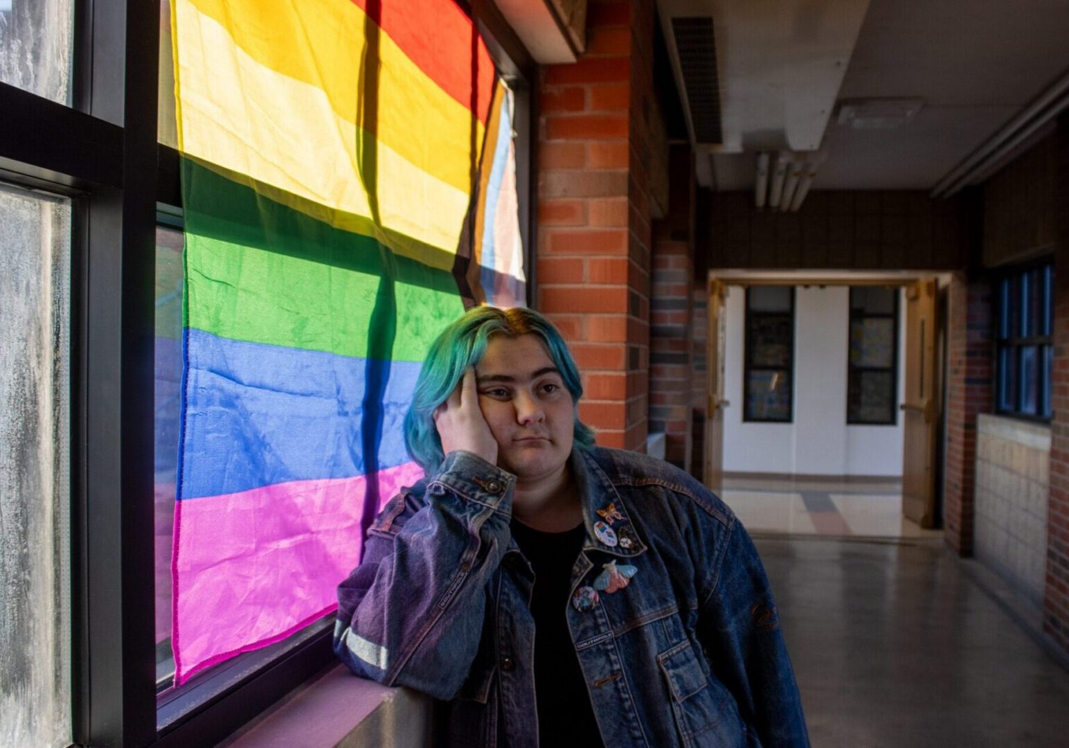 Contemplative person beside window with flag