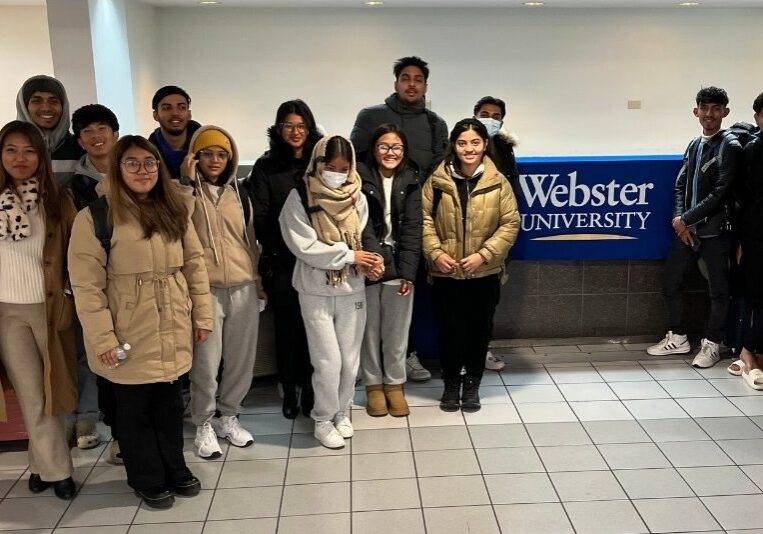 Students posing indoors with luggage.