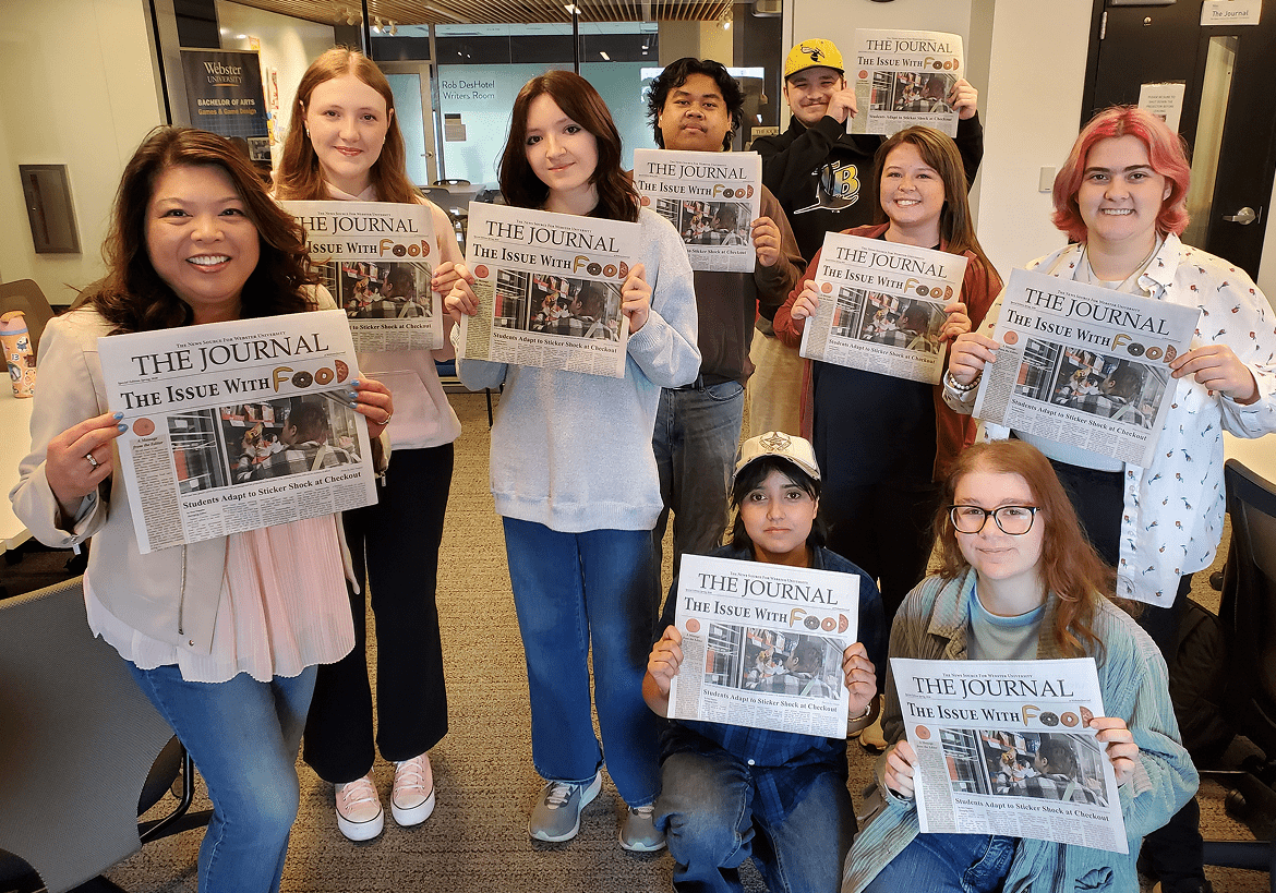 Group holding newspapers and smiling in office