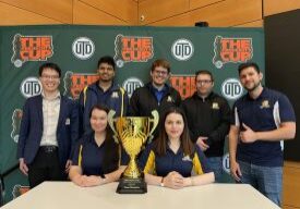 Team posing with trophy in front of banner