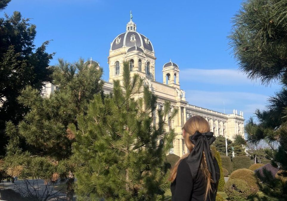 Person admiring historic building through trees