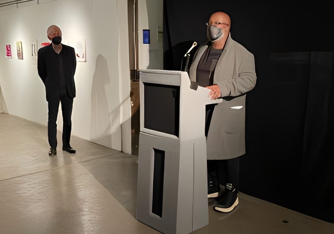 Man speaking at podium with mask