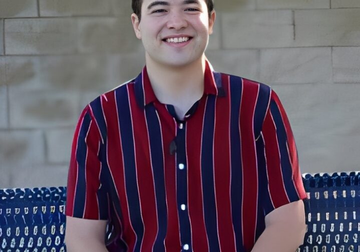 Happy individual seated against a brick wall.
