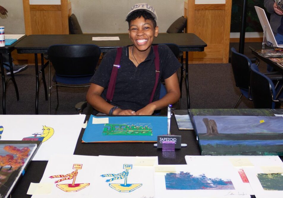 Artist smiling at art display table
