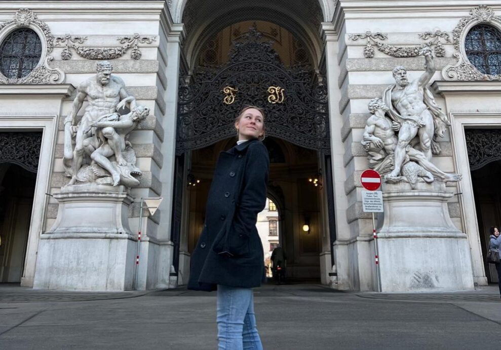 Tourist in black coat near decorative sculptures