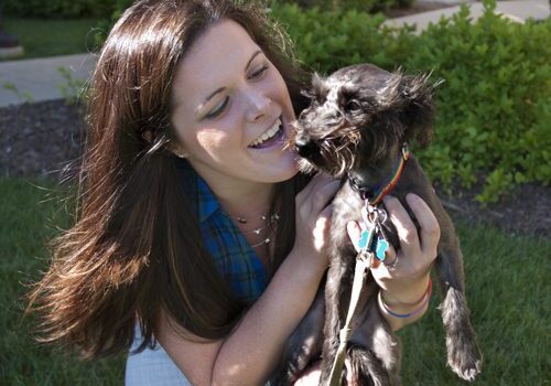 Woman smiling at small dog outdoors