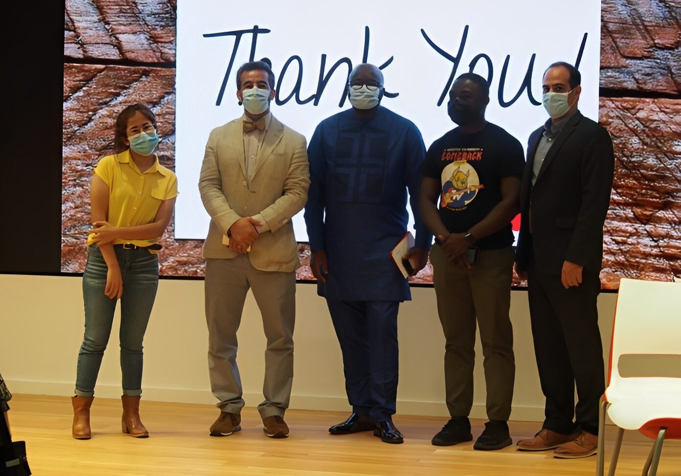 Team standing together, smiling behind masks
