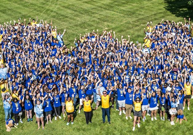 People in blue shirts forming "M" shape