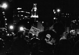 Nighttime protest crowd with city skyline