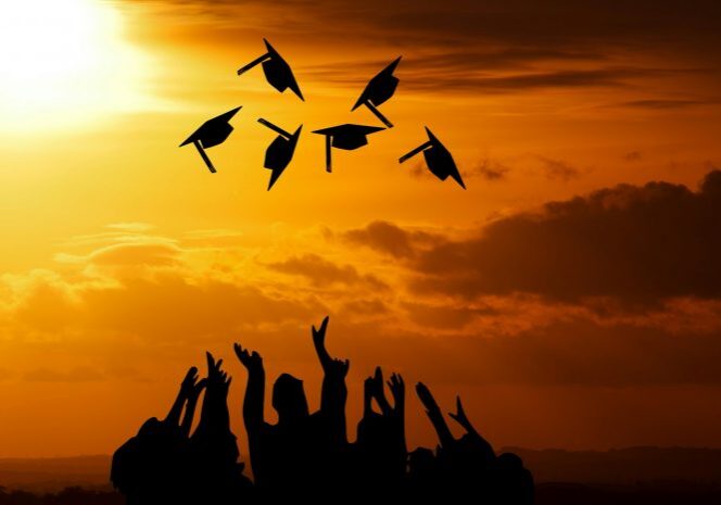 Graduates throwing caps in sunset sky