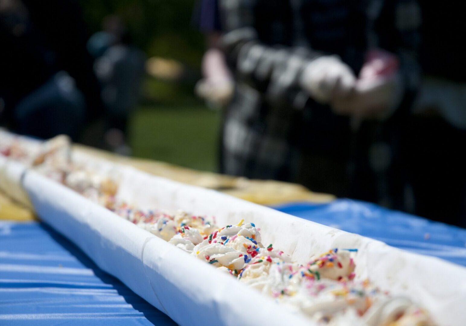 People serving a large ice cream dessert