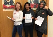 Women posing with papers and posters.