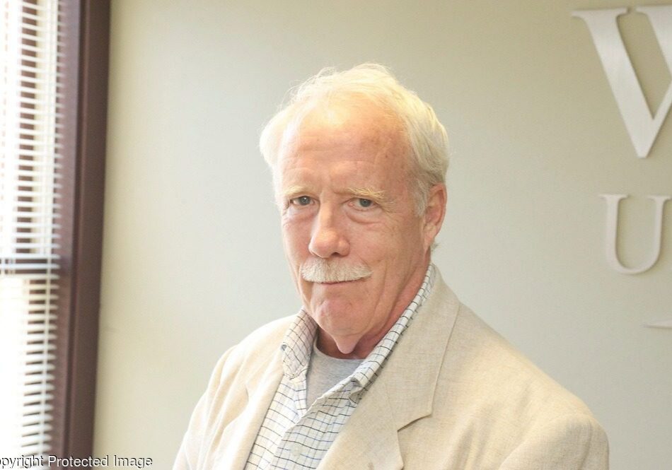 Elderly man in beige suit smiling