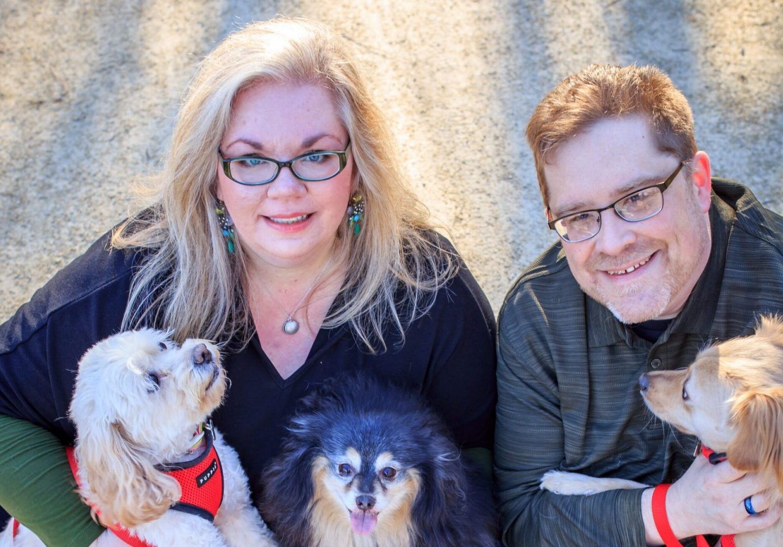 Two people and their three dogs outdoors