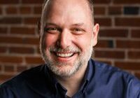 Smiling man in front of brick wall