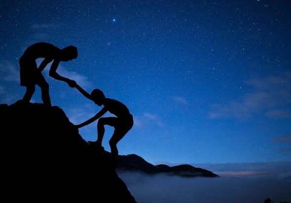 Silhouettes climbing under starry sky