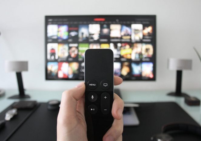 Hand holding remote towards a TV screen