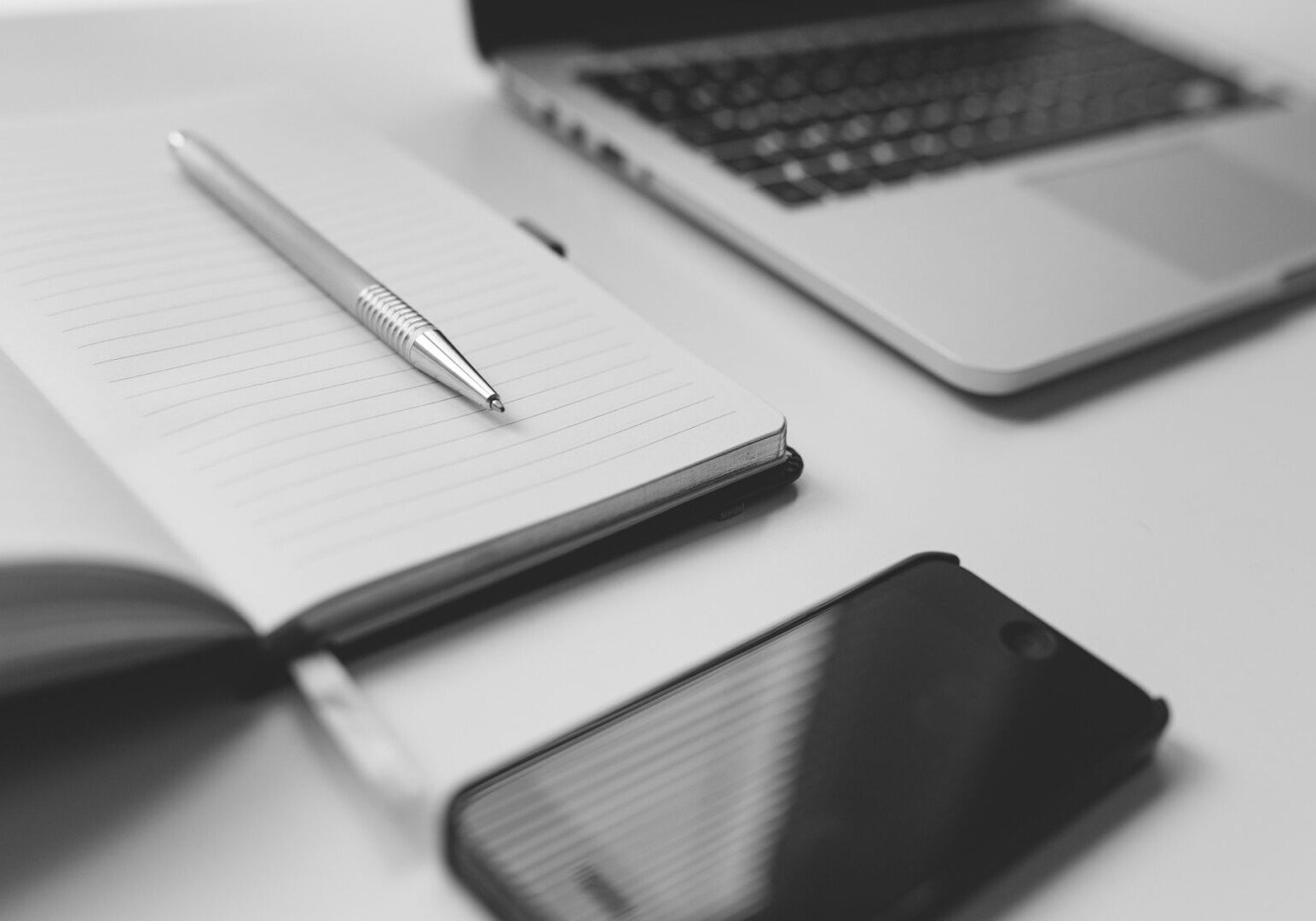 Notebook and pen beside laptop