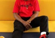Man smiling in red shirt and sneakers