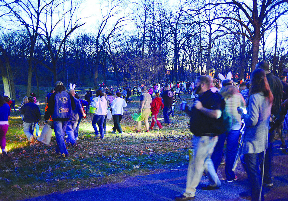 Crowd walking through a park at dusk