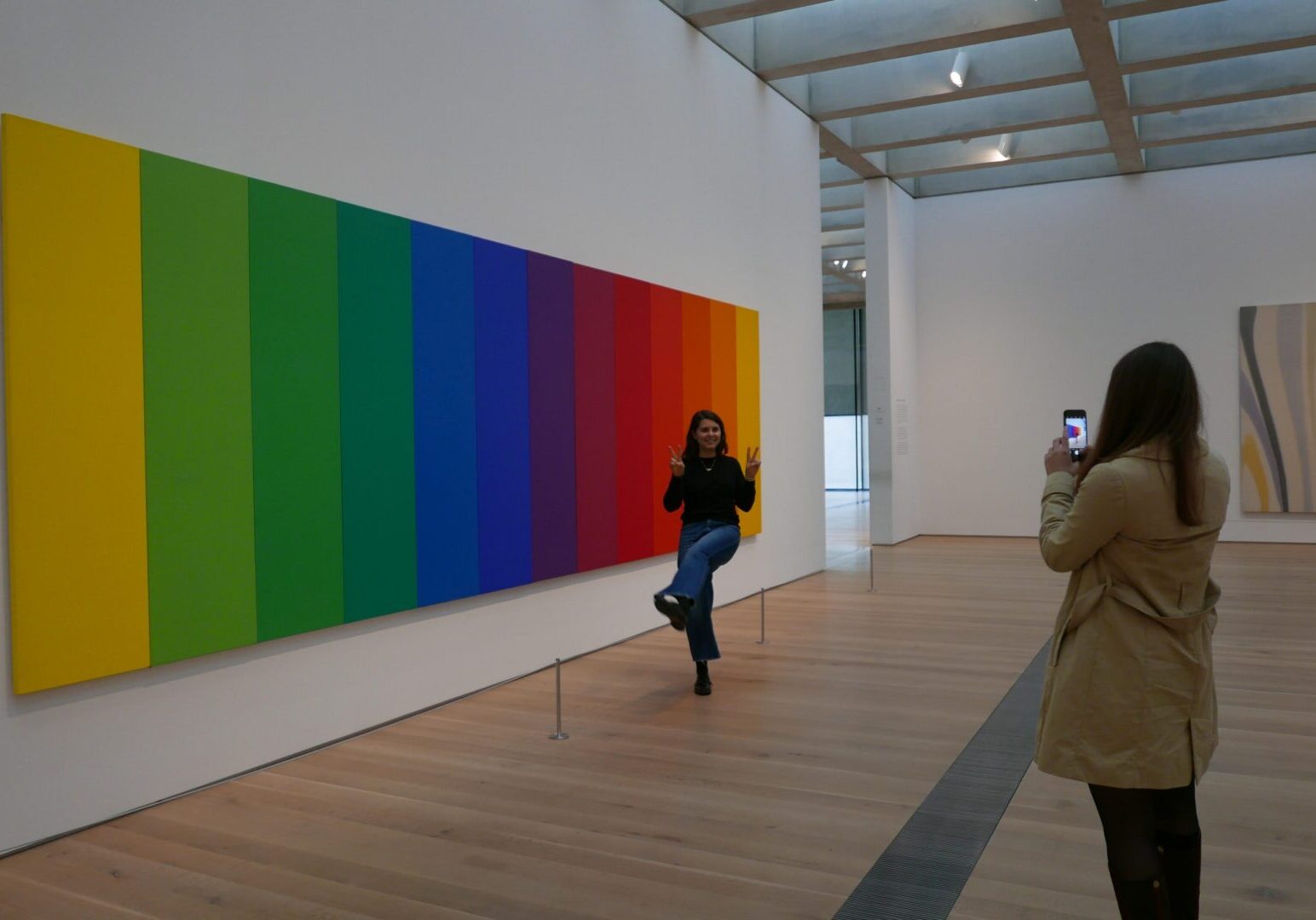 Visitor photographing rainbow-striped artwork
